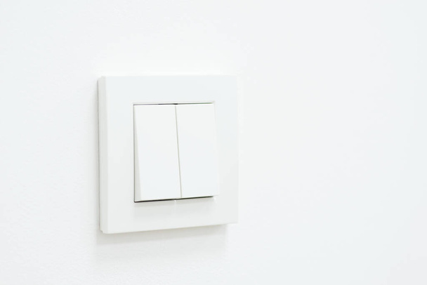 Minimalistyczne zdjęcie białego włącznika światła na ścianie. Włączony włącznik światła na białej ścianie - Zdjęcie, obraz