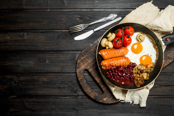 Tradiční anglickou snídani smažená vejce, párky a fazole. Na dřevěné pozadí. - Fotografie, Obrázek