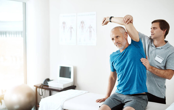 Stretching, physiotherapy and a man with doctor for physical therapy, fitness and health support. Healthcare, sports training and a physiotherapist with a senior patient and arm stretch after injury. - Foto, afbeelding
