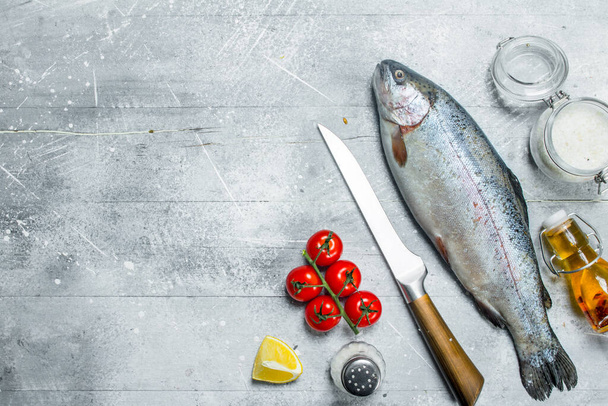 Raw fish salmon with spices, tomatoes and lemon. On a rustic background. - 写真・画像