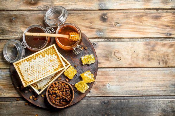 Honey in glass jars and honeycombs on the Board. On a wooden background. - Foto, imagen