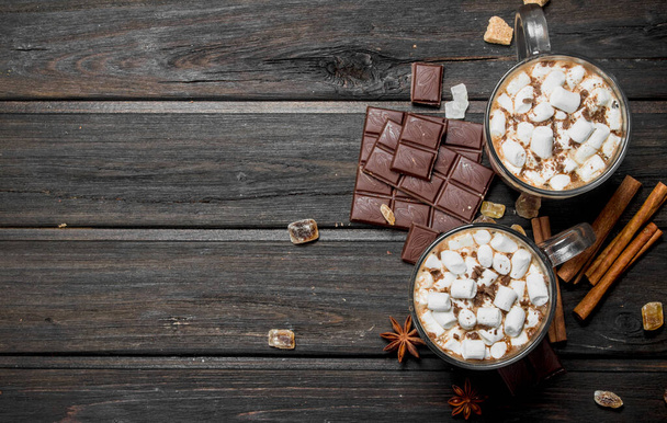 Hot chocolate with cinnamon and marshmallows. On a wooden background. - Photo, image