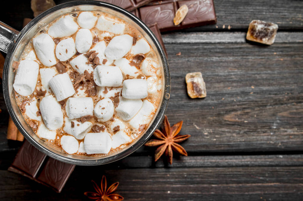 Hot chocolate with cinnamon and marshmallows. On a wooden background. - Foto, imagen