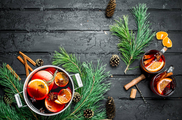 Mulled wine with fir branches and cones. On black rustic background. - Foto, Bild