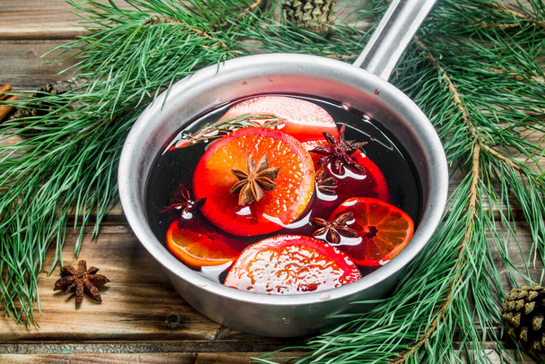 Mulled wine in a pot of spices. On a wooden background. - Foto, afbeelding