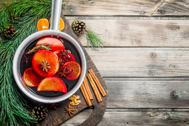 Mulled wine in a pot of spices. On a wooden background. - Foto, imagen