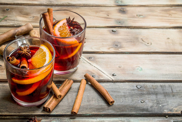 Mulled wine with aromatic seasonings. On a wooden background. - Foto, imagen