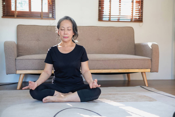 アジアの高齢女性は健康のためにヨガを練習瞑想高齢では、それはリラックスした日に自宅であなたの体の健康を世話することです。健康の概念が - 写真・画像