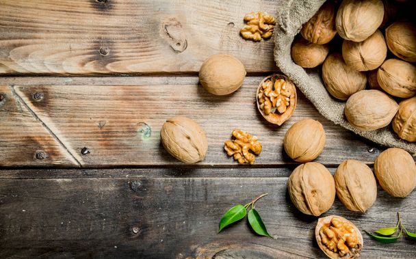 Walnuts in a bag . On a wooden background. - Фото, зображення