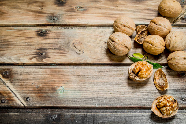 Shelled walnut with green leaves. On a wooden background. - Foto, Imagen