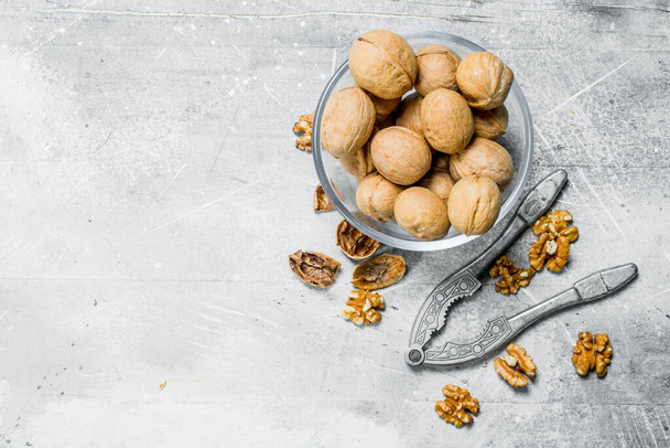 Shelled walnuts with a Nutcracker . On a rustic background. - Foto, afbeelding