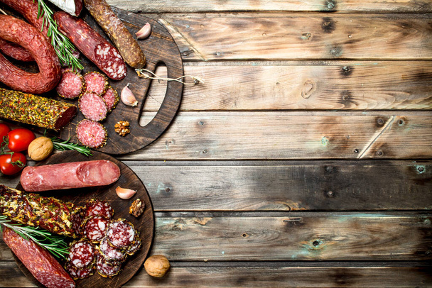 Various types of salami on a Board with nuts. On a wooden background. - Photo, Image