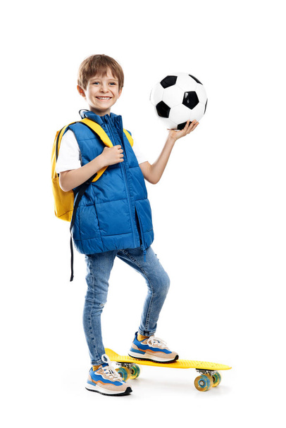 Stylish little boy with skateboard and backpack holding soccer ball on white background. Back to School - Φωτογραφία, εικόνα