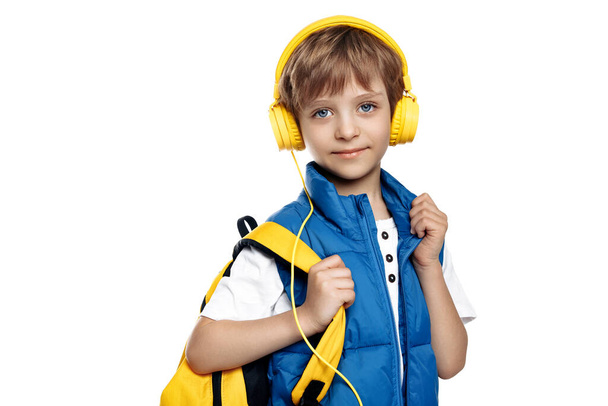 Trendy little boy wearing headphone and yellow backpack looking to camera on white background. Back to School - Foto, Bild