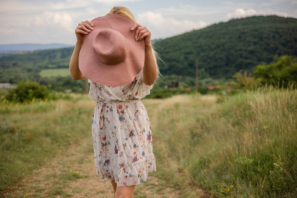 красива молода жінка в капелюсі і сукня з букетом квітів у полі
 - Фото, зображення