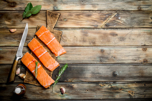 Raw salmon fish steaks with herbs and garlic. On a wooden background - Fotoğraf, Görsel