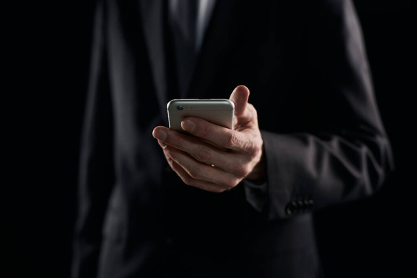 Businessman casual messaging on the phone on dark background - Foto, immagini