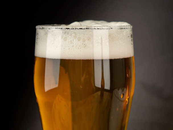 A glass of cold beer on a dark background. Glass of beer close-up. - Photo, Image