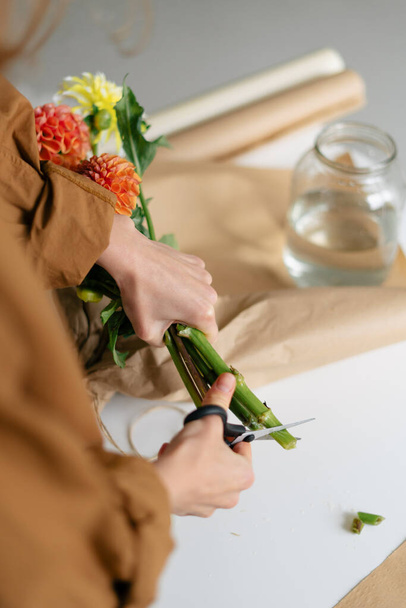 Immagine verticale di una fiorista donna che taglia i fiori di dalia prima di confezionarli in un bouquet. Immagine per il vostro disegno - Foto, immagini
