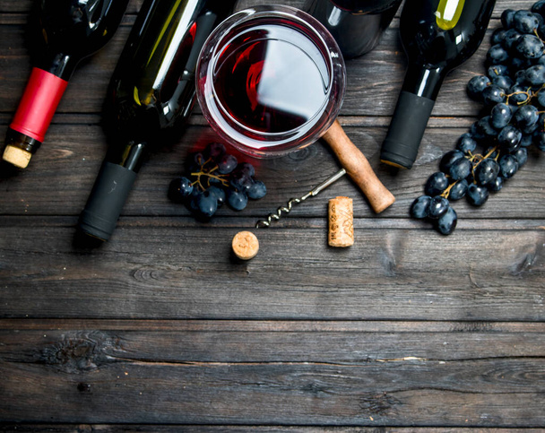 ワインの背景。赤ワインとコルク栓抜きのブドウ。木製の背景に. - 写真・画像