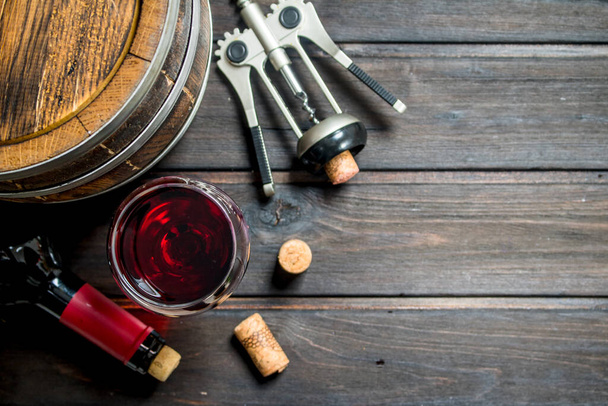 Wine background. A barrel of red wine with a corkscrew. On a wooden background. - Фото, изображение