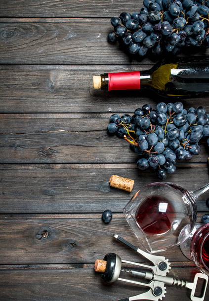 Wine background. Red wine with corkscrew. On a wooden background. - Zdjęcie, obraz
