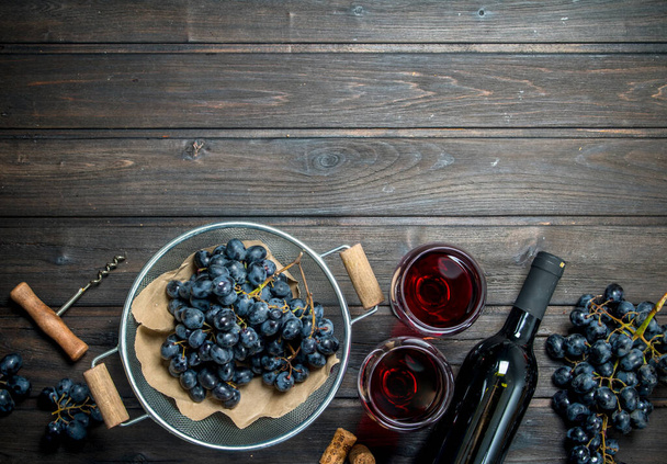 Wine background. Red wine in glasses with grapes. On a wooden background. - Zdjęcie, obraz