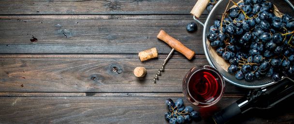 Винний фон. Червоне вино в келихах з виноградом. На дерев'яному тлі
. - Фото, зображення