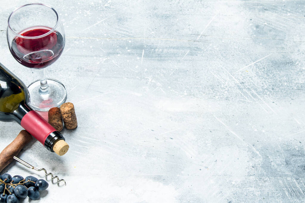 Wine background. Red wine with a grapes and a corkscrew. On a rustic background. - Foto, Imagem