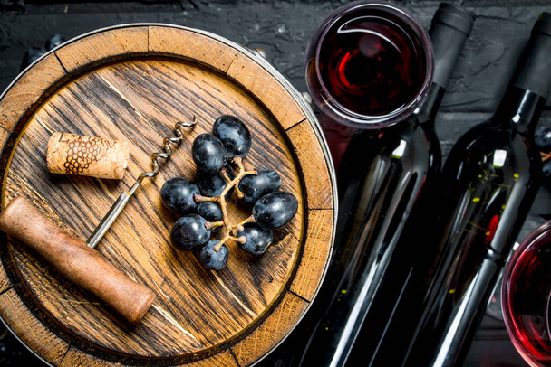Wine background. Red wine with grapes and an old barrel. On a black rustic background. - Zdjęcie, obraz