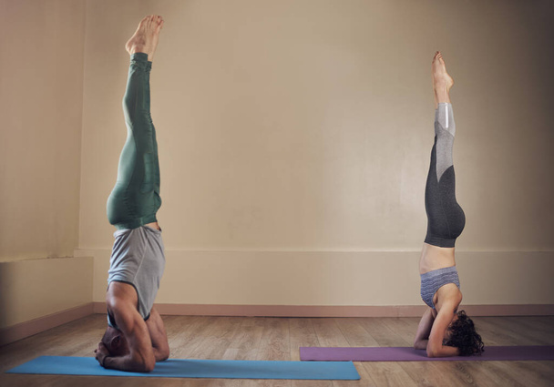 Hold and breathe. Full length shot of two unrecognizable yogis holding elbow stands during an indoor yoga session - Zdjęcie, obraz