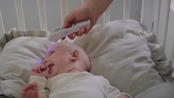 泣いている赤ん坊に温度を測定する認識できない女性。8Kでレッドヘリウムカメラで撮影. - 映像、動画