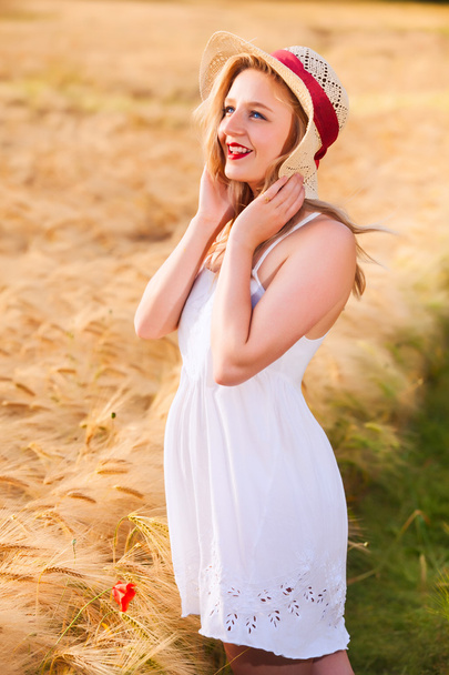 Lonely beautiful young blonde girl in white dress with straw hat - Foto, afbeelding