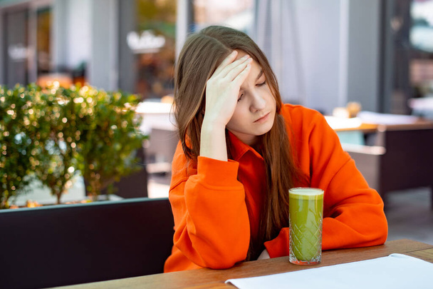 teen girl is upset. unhappy girl does not want to drink green vegetable juice - Fotografie, Obrázek
