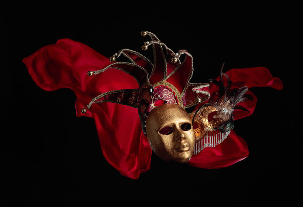 Carnaval maskers op een zwarte achtergrond met flutters rode doek. Kopieerruimte. - Foto, afbeelding