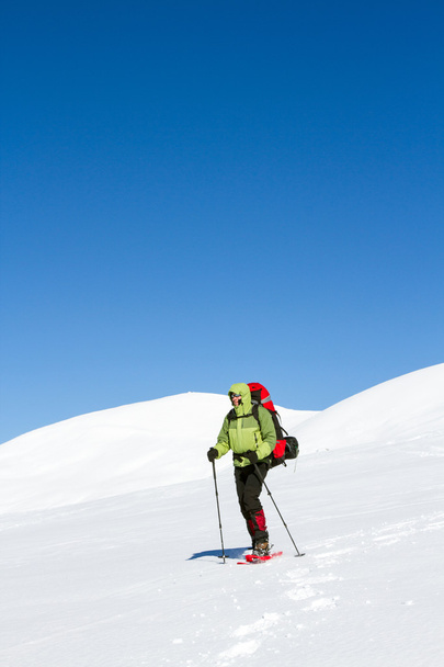 Winter hiking in the mountains on snowshoes with a backpack and tent. - Foto, Bild