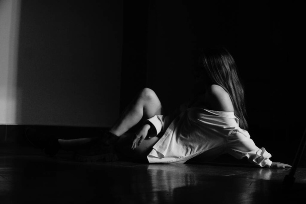 černá a bílá fotografie krásné mladé dívky pouze v jedné bílé košili přes její nahé tělo pózuje ve studiu - Fotografie, Obrázek