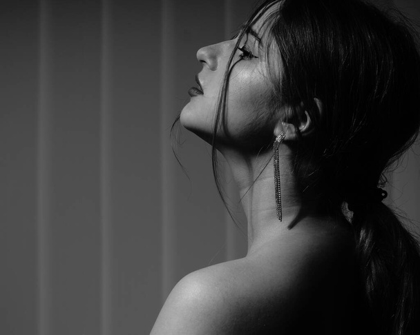 черно-белое фото красивой молодой девушки в одной белой рубашке над ее обнаженным телом, позирующей в студии - Фото, изображение