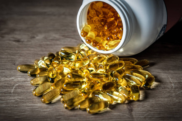 Yellow capsules of omega-3 with bottle, fatty acid pills, nutritional supplement. Healthcare and medical theme - 写真・画像