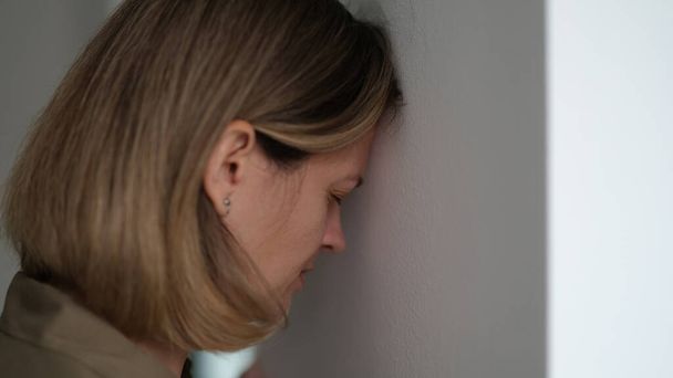 Fatigué femme déprimée frapper sa tête contre le mur. Concept de situations désespérées - Photo, image