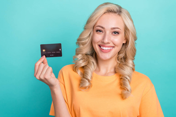 Portrait of adorable lovely person with wavy hairdo wear stylish t-shirt fingers hold credit card isolated on turquoise color background. - Φωτογραφία, εικόνα