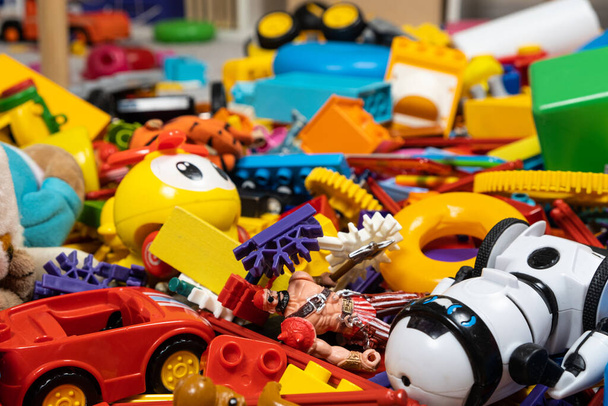 Una abundancia de juguetes en la habitación de los niños, una gran cantidad de piezas de plástico multicolor de diseñadores, piezas de repuesto para juguetes, figuritas y cubos - Foto, imagen