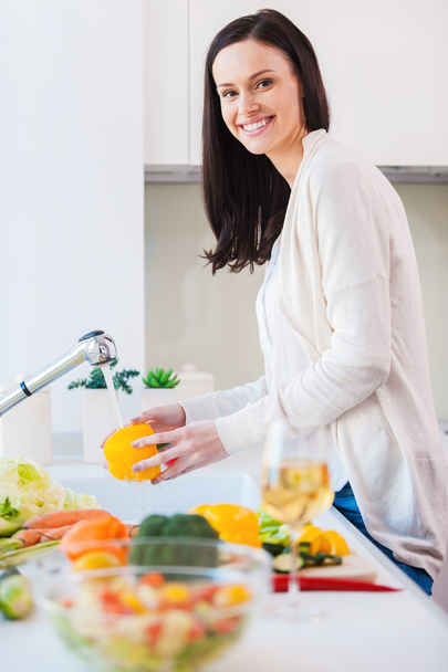 Молодая женщина моет овощи для салата
 - Фото, изображение