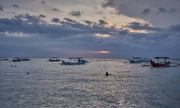Kuta 'daki Pantai Jerman (Alman Sahili), Bali Endonezya' da günbatımı. Okyanusta kayıkları gösteren bir çekim. - Fotoğraf, Görsel