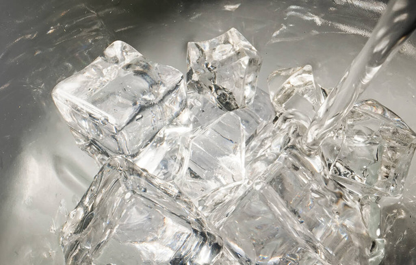 Water is poured into a glass with ice. - Foto, imagen