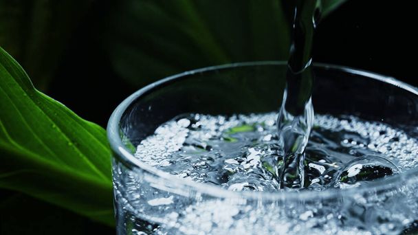 Koolzuurhoudend mineraalwater wordt in een glas gegoten. - Foto, afbeelding