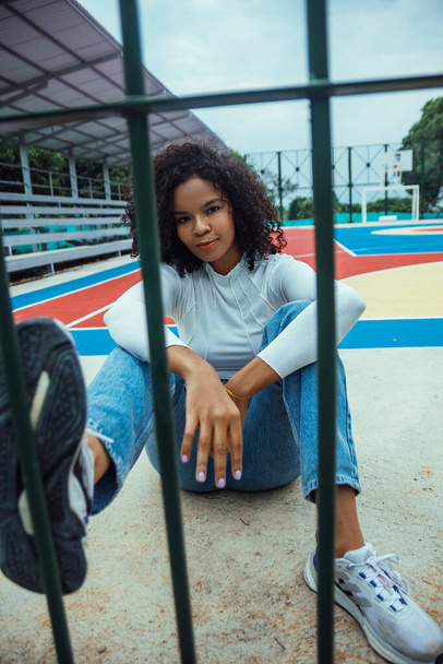 beautiful woman with dark and curly skin in a photo session on the court - Zdjęcie, obraz