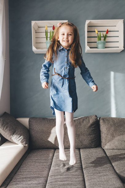 Happy little girl jumping on couch at home. Childhood - Fotografie, Obrázek
