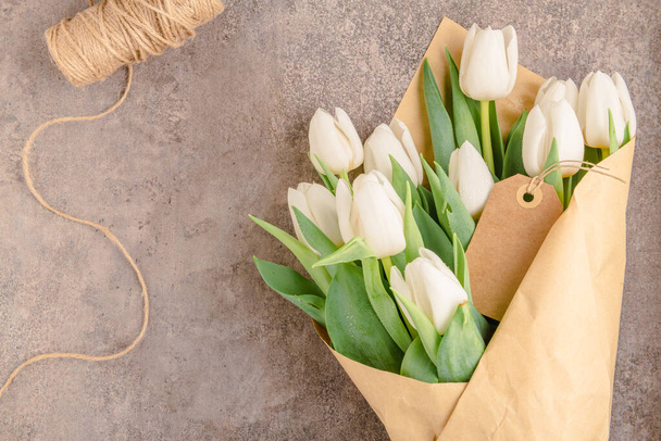 Bouquet de tulipes blanches sur fond gris, espace de copie. Pâques. Vue du dessus - Photo, image