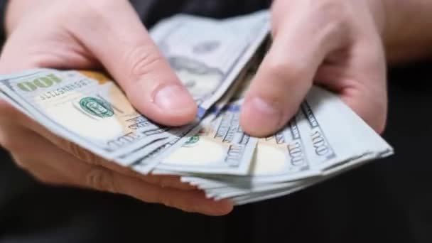 Close-up van een zakenman die 100 dollarbiljetten in contanten telt. Bedrijfs- en financieringsconcept. - Video